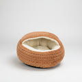 A round, waffle-textured pet bed in a warm tan-brown color with a soft cream-colored fleece lining, shown on a solid white background.