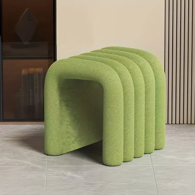 A set of five modern, U-shaped poufs or low stools upholstered in a textured light green bouclé fabric, arranged in a row on a light gray tiled floor.