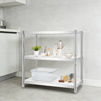 A three-tier kitchen organizer shelf with a chrome silver metal frame and white shelves, styled with kitchenware and food items in a modern kitchen setting.