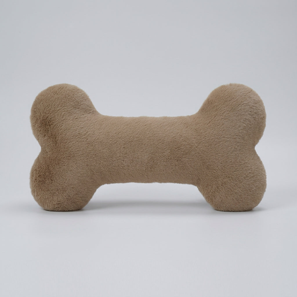Beige bone-shaped pillow on a textured surface with a magazine underneath