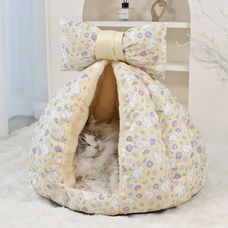 Cat lying in a floral-patterned pet bed with a large bow on top.