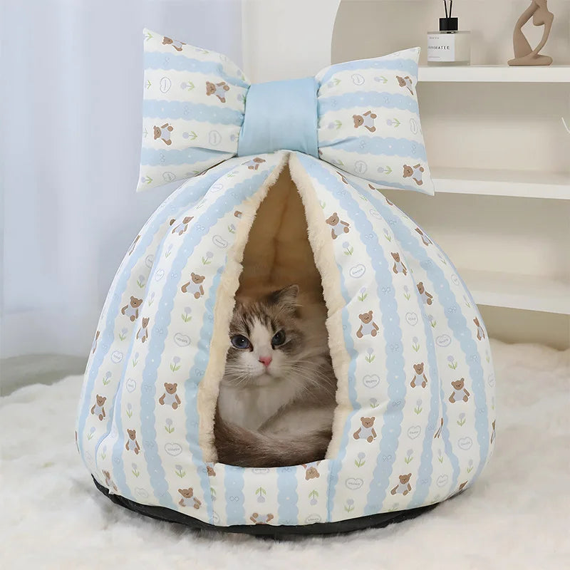 Cat peeking out from a blue and white striped pet bed with a bow on top.