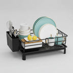 Dish drying rack with plates, bowls, and utensils on a kitchen counter.