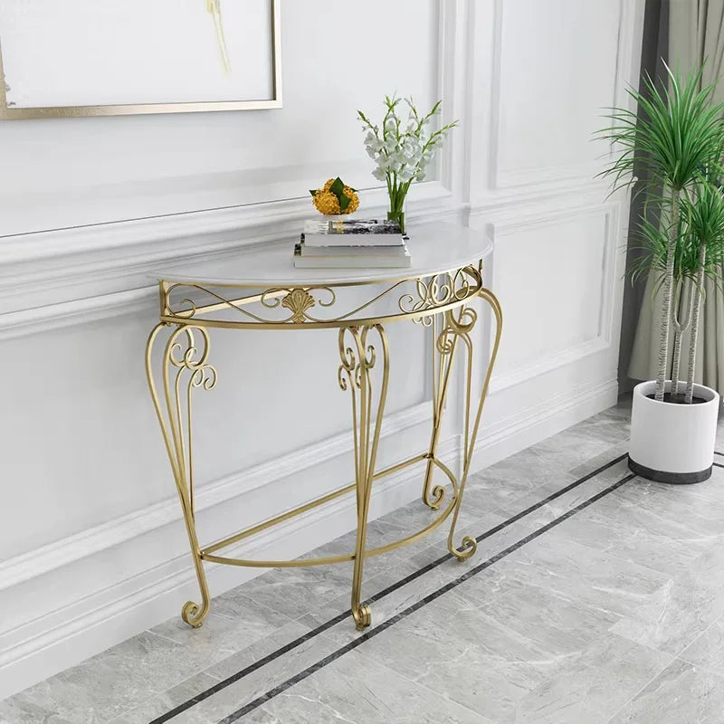 Gold decorative console table in a room with white walls and a plant.