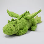 Green plush dragon toy on a pink surface with a blurred indoor background