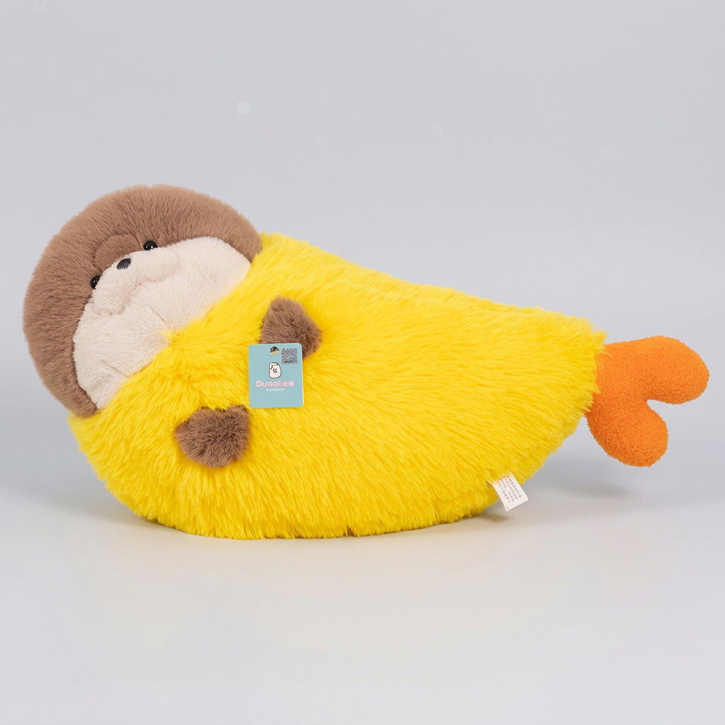 A plush toy pillow shaped like a sleeping animal wrapped in a bright yellow blanket, resting on a beige sofa in a softly lit room. The toy has brown and cream fur on its head, a yellow body, and an orange tail.