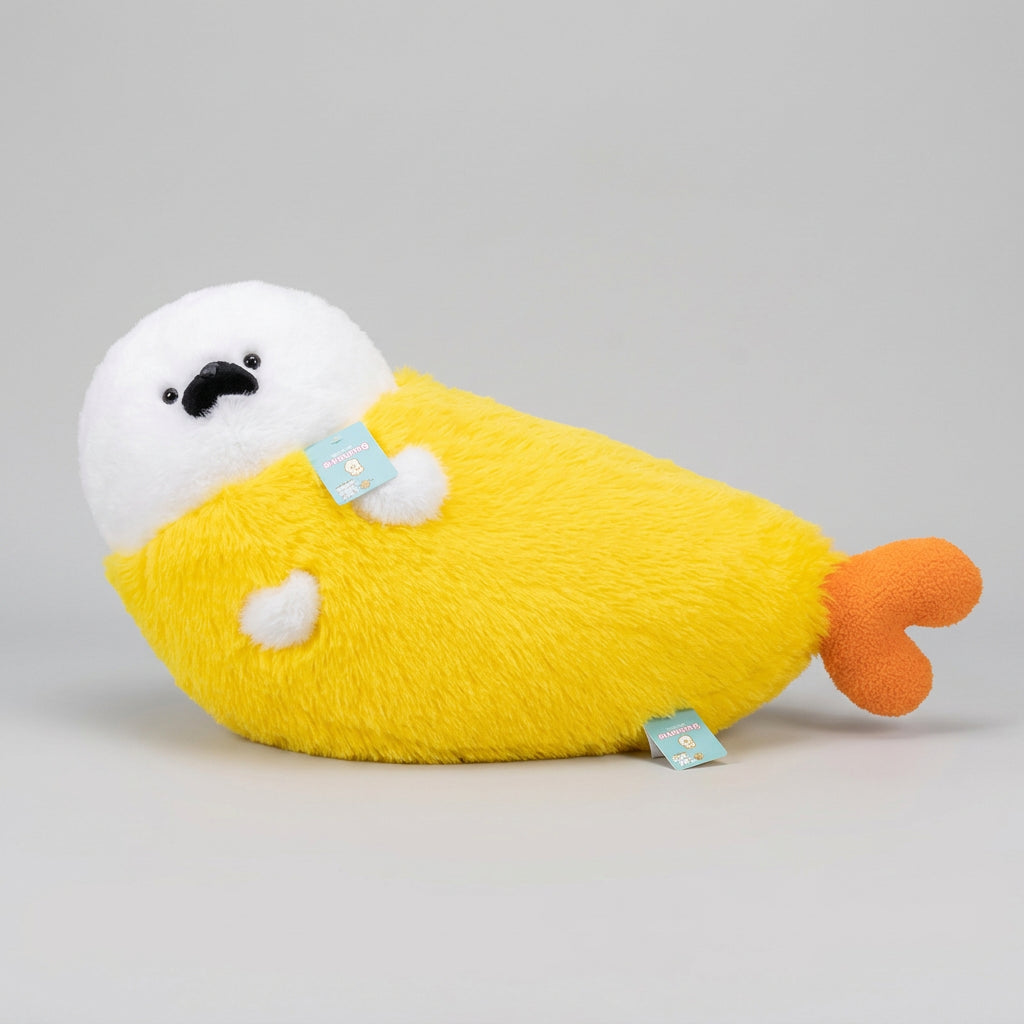 A yellow and white plush seal pillow with an orange tail, resting on a beige sofa in a cozy room setting.