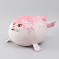 Pink plush toy resembling a seal on a woven mat with a light background