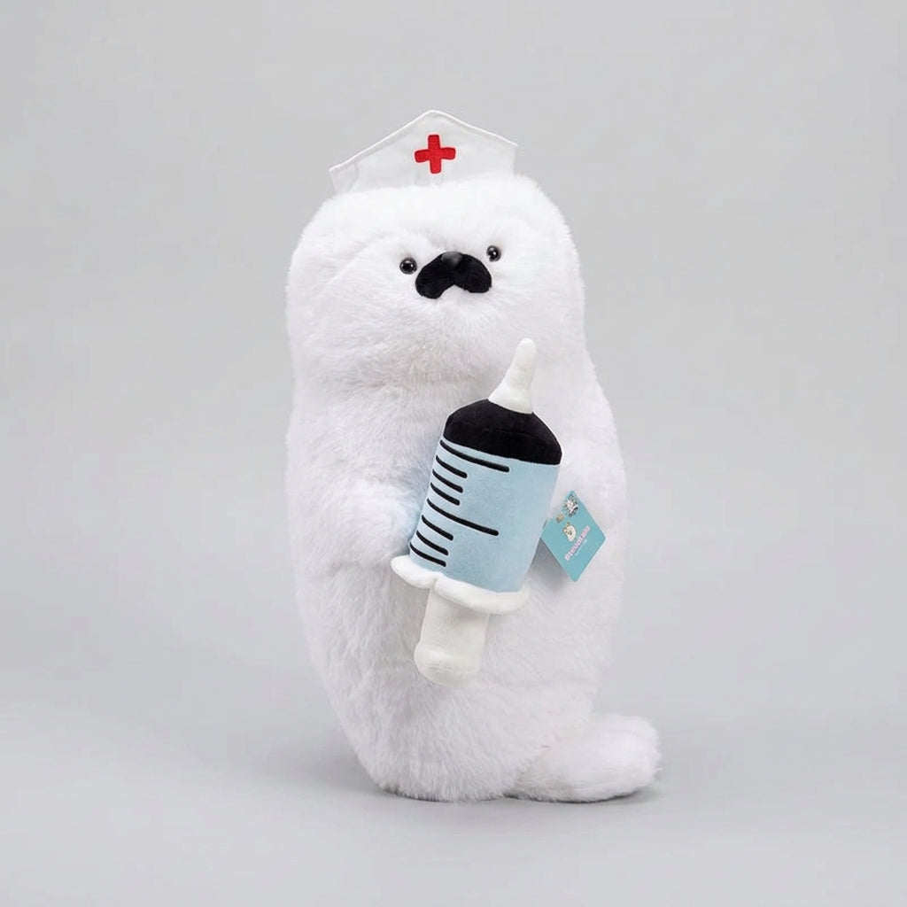 A white plush polar bear toy wearing a nurse hat and holding a syringe, resting on a cream-colored sofa in a bright indoor setting.