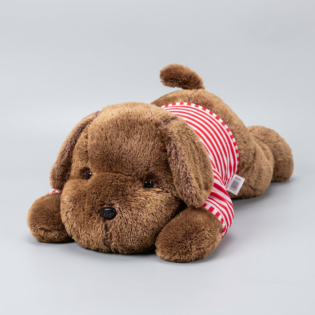 Brown plush dog toy with a red and white striped shirt on a bed.