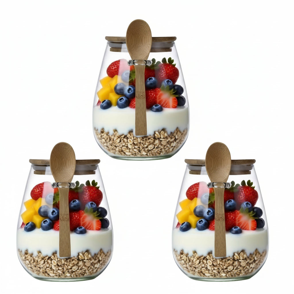 Three glass jars with fruit and granola, each containing a wooden spoon, on a white background.