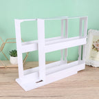 White magazine rack on a wooden surface with a light green wall in the background